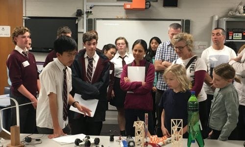 students and peers gathered around a project